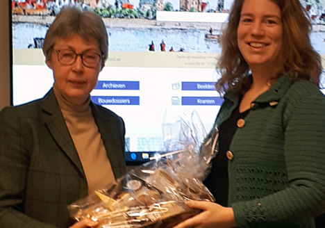 Linda Folkers, winnaar van de wedstrijd voor de nieuwe naam van RHC Zuidoost Utrecht, ontvangt van directeur-archivaris Ria van der Eerden haar prijs.