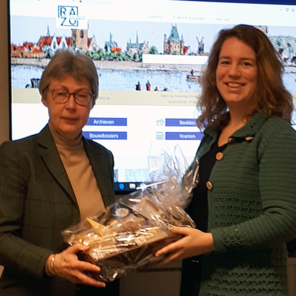 Linda Folkers, winnaar van de wedstrijd voor de nieuwe naam van RHC Zuidoost Utrecht, ontvangt van directeur-archivaris Ria van der Eerden haar prijs.