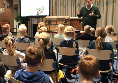 Dhr. Postema vertelt, met een oude kist en archiefstukken aan de kinderen het verhaal. Foto C. Molhoek