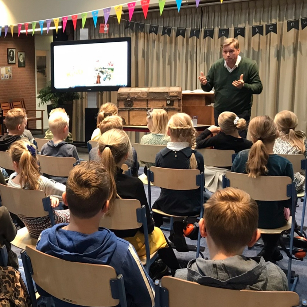 Dhr. Postema vertelt, met een oude kist en archiefstukken aan de kinderen het verhaal. Foto C. Molhoek